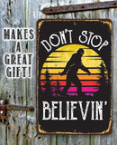 The Don't Stop Believing Big Foot Metal Sign by Lone Star Art features a Sasquatch silhouette against a sunset on wood—a perfect cabin decor or sasquatch gift. Text reads "DON'T STOP BELIEVIN." Makes a great gift!.