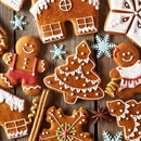 An assortment of decorated gingerbread cookies shaped like people, houses, a Christmas tree, and snowflakes rests on a wooden surface, with cinnamon sticks and star anise. A touch of The Spice Lab Organic Ground Allspice by The Spice Lab adds warmth to the festive scene.