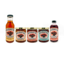 The Brushfire Farms El Jefe Bundle features five beautifully arranged products—a bottle of glaze, three jars from the Three Amigos Jam set, and a prickly pear simple syrup—all sporting matching orange-themed labels, making it the perfect set for crafting a flavorful gift box.