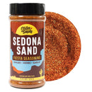 A jar of Chiles and Smoke Sedona Sand Fiesta Seasoning, a bold Southwest BBQ seasoning crafted with chiles, herbs, and garlic. Next to the jar is a close-up showcasing the reddish sugar-free BBQ rub blend. The label features vibrant colors and a desert-inspired motif.