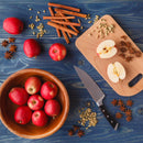 Whole and halved red apples rest in a wooden bowl and on a cutting board beside a knife, surrounded by cinnamon sticks, star anise, and cardamom—classic ingredients featured in The Spice Lab Apple Pie Spice Blend by The Spice Lab. All are beautifully arranged on a blue wooden table, capturing the cozy aroma of this seasonal blend that’s perfect for autumn baking.