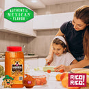 A woman and a young girl slice vegetables in a bright kitchen. A Rico Rico Habanero Chile Powder Shaker by Rico Rico sits in the foreground. Text reads Authentic Mexican Flavor. Various vegetables and hot spices are scattered across the counter.