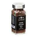 A transparent glass jar with a silver lid holds whole brown mustard seeds, ideal for pickling or crafting homemade mustard. The black label displays: The Spice Lab Brown Mustard Seeds Whole, Net Wt. 3 oz. (85g).