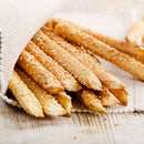 Several sesame-covered breadsticks, generously topped with The Spice Lab Organic Hulled Sesame Seeds and partially wrapped in a white cloth, resting on a light wooden surface—a perfect addition to your baking or to serve alongside vibrant stir-fries.