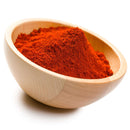 A wooden bowl filled with a mound of vibrant red-orange The Spice Lab Cayenne Pepper X-Hot Ground seasoning, set against a white background.