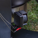 Close-up of the Flame Boss 400 WiFi Kamado Smoker Controller Kit (FB400-K) by Flame Boss, with cables attached to a metallic surface and grass in the background—ideal for upgrading your Kamado grill with precise outdoor temperature control.
