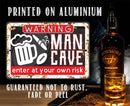 The Enter At Your Own Risk - Metal Sign by Lone Star Art is a funny aluminum wall decor with beer, cigar, and football icons—guaranteed not to rust or fade. A whiskey bottle and glass sit beside it.