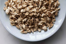 A white plate filled with World Spice Chopped Ginger from World Spice, displaying light brown and beige tones, set on a light surface—perfect for crafting a warming infusion.