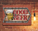 The Good Beer - Metal Sign by Lone Star Art features a frothy beer mug and “GOOD BEER” text—vintage wall decor for your home bar. A hanging light bulb glows close by.