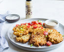 A plate of crispy fritters garnished with green onions and cherry tomatoes, served with dipping sauce. In the background sits a quart of Terrapin Ridge Farms Bacon Aioli from Terrapin Ridge Farms, perfect as a burger condiment.