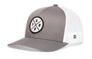 The Haka Hat PNW X Trucker Hat features a gray and white design with mesh panels, a snapback closure, and a front patch displaying the letters PNW and a tree in an intersecting cross pattern.