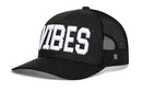 The Haka Hat VIBES Trucker Hat features a black solid front panel with bold white "VIBES" lettering, curved brim, mesh sides and back, comfort-fit sweatband, and snapback closure—perfect for all-day wear.