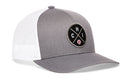 The Haka Hat Chicago Trucker Hat is a silver snapback trucker hat with a black circular patch featuring crossed lines, the letters C and H, I, plus a small baseball icon—classic Chicago style.