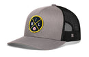 The Haka Hat Milwaukee Trucker Hat | MIL X Baseball Snapback by Haka Hat is a gray and black mesh-back hat with a front circular patch featuring a yellow border, crossed yellow lines, “M,” “I,” “L,” and a small baseball graphic.