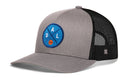 The Haka Hat Dallas Trucker Hat is a gray and black mesh snapback featuring a blue circular DAL patch with an orange basketball on the front.