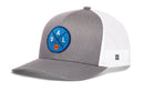 The Haka Hat Dallas Trucker Hat | DAL X Basketball Snapback features a gray front, white mesh sides/back, and a round blue patch with D, A, L around an orange basketball in the popular Haka 5.0 trucker snapback style.