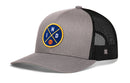 The Haka Hat Indiana Trucker Hat by Haka Hat is a gray and black mesh snapback featuring a circular blue patch with yellow crossed lines, the letters “N” and “D,” and a small orange basketball at the intersection.