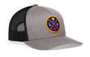The Haka Hat Los Angeles Trucker Hat is a gray and black mesh snapback featuring an embroidered LA X Basketball patch with a palm tree, “LA” letters, and a basketball icon on a purple background.