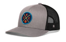 The Haka Hat Oklahoma City Trucker Hat | OKC X Basketball Snapback by Haka Hat features a gray front with a round basketball patch showing K, O, C on navy, and a black mesh back with a small H logo for classic trucker style.