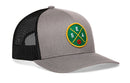 The Haka Hat Seattle Trucker Hat is a gray and black mesh snapback, featuring a round green, yellow, and gold SEA basketball patch on the front.