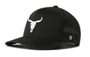 The Haka Hat Bull Skull Performance 5-Panel Hat is a black Flexfit snapback featuring a white bull skull logo front, side ventilation holes, comfortable Flexfit sweatband, and a small H emblem near the brim.