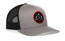 The Haka Hat Carolina Hockey Trucker Hat | Black CAR X Snapback features a gray and black mesh design with a round patch displaying crossed hockey sticks and the letters C A R in white outlined in red. This Haka Hat signature 5.0 trucker is the perfect North Carolina hat for any hockey fan.