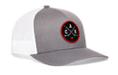 The Haka Hat Carolina Hockey Trucker Hat | Black CAR X Snapback by Haka Hat features a gray and white design with a round black and red patch displaying two crossed hockey sticks, the letters C A R, and a small red puck at the bottom. This Haka signature 5.0 trucker is an ideal addition to any North Carolina hat collection.