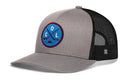 Grey and black Haka Hat Colorado Hockey Trucker Hat featuring a circular patch with crossed hockey sticks, a puck, and the letters C, O, and L.