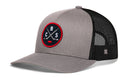 The Haka Hat Columbus Hockey Trucker Hat | CBS X Snapback features a gray and black design with a breathable mesh back and an embroidered red and black circular CBS X patch displaying two crossed baseball bats and the letters C, B, and S.