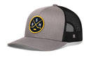 The Haka Hat Nashville Hockey Trucker Hat | NSH X Snapback by Haka Hat is a gray and black mesh trucker hat featuring a round yellow and black patch with crossed hockey sticks, S and N lettering, plus a small H on the mesh side—an ideal addition for any Nashville hockey trucker hat collector.