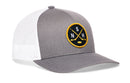 The Haka Hat Nashville Hockey Trucker Hat | NSH X Snapback features a gray and white mesh snapback design with a round black and yellow patch displaying two crossed hockey sticks, a puck, and the letters S, N, H—capturing the essence of Nashville hockey style.