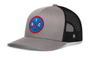 The Haka Hat New York Hockey Trucker Hat (NYC X Snapback) features gray and black mesh construction with a blue and red circular patch showcasing two crossed hockey sticks, NYC lettering, and a hockey puck. Designed for comfort and style, this Haka Hat includes a curved brim and an adjustable snapback closure for the perfect fit.
