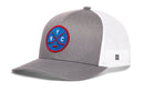 Introducing the Haka Hat New York Hockey Trucker Hat | NYC X Snapback—a gray and white snapback trucker hat by Haka Hat, featuring a bold blue circular patch on the front with crossed hockey sticks, prominent NYC lettering, and an eye-catching red outline—an ideal pick for any New York Hockey Trucker Hat fan.