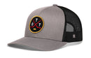 The Haka Hat Ottawa Hockey Trucker Hat | OTT X Snapback is a grey and black snapback featuring a round patch on the front with two crossed red hockey sticks, a yellow hockey puck, and the letters O T T—a signature 5.0 trucker style that’s perfect for any fan.