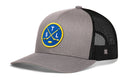 The Haka Hat St. Louis Hockey Trucker Hat | STL X Snapback by Haka Hat features a gray and black snapback design with a black mesh back for comfort, and is accented by a blue circular patch displaying crossed yellow hockey sticks, a puck, and the letters S, T, and L for that classic St. Louis hockey look.