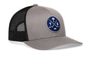Grey and black Haka Hat Tampa Bay Hockey Trucker Hat featuring a circular patch with crossed hockey sticks, a palm tree, a puck, and the letters T and B.