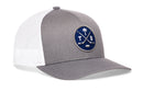 Grey and white Haka Hat Tampa Bay Hockey Trucker Hat featuring a circular patch with crossed hockey sticks, a palm tree, a puck, and the letters T and B.