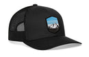 The Haka Hat Mountains and Sky Trucker Hat by Haka Hat is a black mesh outdoors snapback with a curved brim and front shield patch featuring mountains, trees, and blue sky.