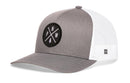 The Haka Hat PNW Trucker Hat in gray and white features a mesh back, comfort-fit sweatband, and a circular front patch with crossed lines, the letters PNW, and a pine tree.