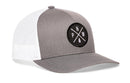The Haka Hat PNW Trucker Hat features a gray-white design, black circular patch with crossed arrows, PNW letters, tree icon, and a comfort-fit sweatband for all-day wear. Also called the Gray-White PNW X Snapback by Haka Hat.