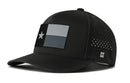 The Haka Hat Texas Flag Performance 5-Panel Hat features a black design with a rectangular black, white, and gray Texas flag patch, Flexfit sweatband, side H logo, ventilating perforations, and water-repellent fabric.