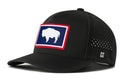 The Haka Hat Wyoming Flag Performance 5-Panel Hat features a black design with a WY Buffalo patch, small ventilation holes, an H logo on the brim, and a Flexfit® sweatband for comfort.