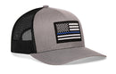 The Haka Hat Thin Blue Line Trucker Hat is a gray and black snapback featuring an embroidered black-and-white American flag with a blue stripe on the front panel.