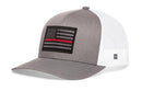 The Haka Hat Thin Red Line Trucker Hat in gray-white features a black embroidered American flag with a red stripe, mesh back, structured front, and the signature HAKA trucker design.