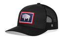 The Haka Hat Wyoming Flag Trucker Hat is a black snapback with mesh back and a front patch showing a white buffalo silhouette on blue, outlined in red.