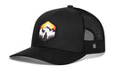Introducing the Haka Hat Hexagon Mountain Trees Trucker Hat by Haka Hat—a classic black adventure snapback featuring a mesh back and an eye-catching front patch with mountain trees in a hexagon design, accented by a sunset scene in orange, yellow, and white.