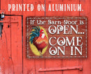 The Lone Star Art “If The Barn Door Is Open, Come On In - Metal Sign” features a red barn door, a rooster welcome sign, and is printed on aluminum for indoor or outdoor use.