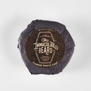 A round puck of natural shave soap from The Immaculate Beard, wrapped in black paper with a brown label that reads “Shave Soap Puck | The Immaculate Beard, Premium Gentlemen’s Grooming Supply”—specially crafted for sensitive skin.