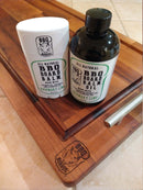 The BBQ Boards® BBQ Board Balm® Care Pair Wax and Oil includes a rosemary and lime scented stick balm and oil bottle, ideal for cutting board care, both featuring metal handle wooden cutting boards in the set.