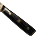 Close-up of the Spaceman Knives Interstellar Boning Knife handle, featuring a black hexagonal-patterned grip and three metal rivets—one with a floral design. Ideal for precision trimming, it rests on a smooth, light surface.